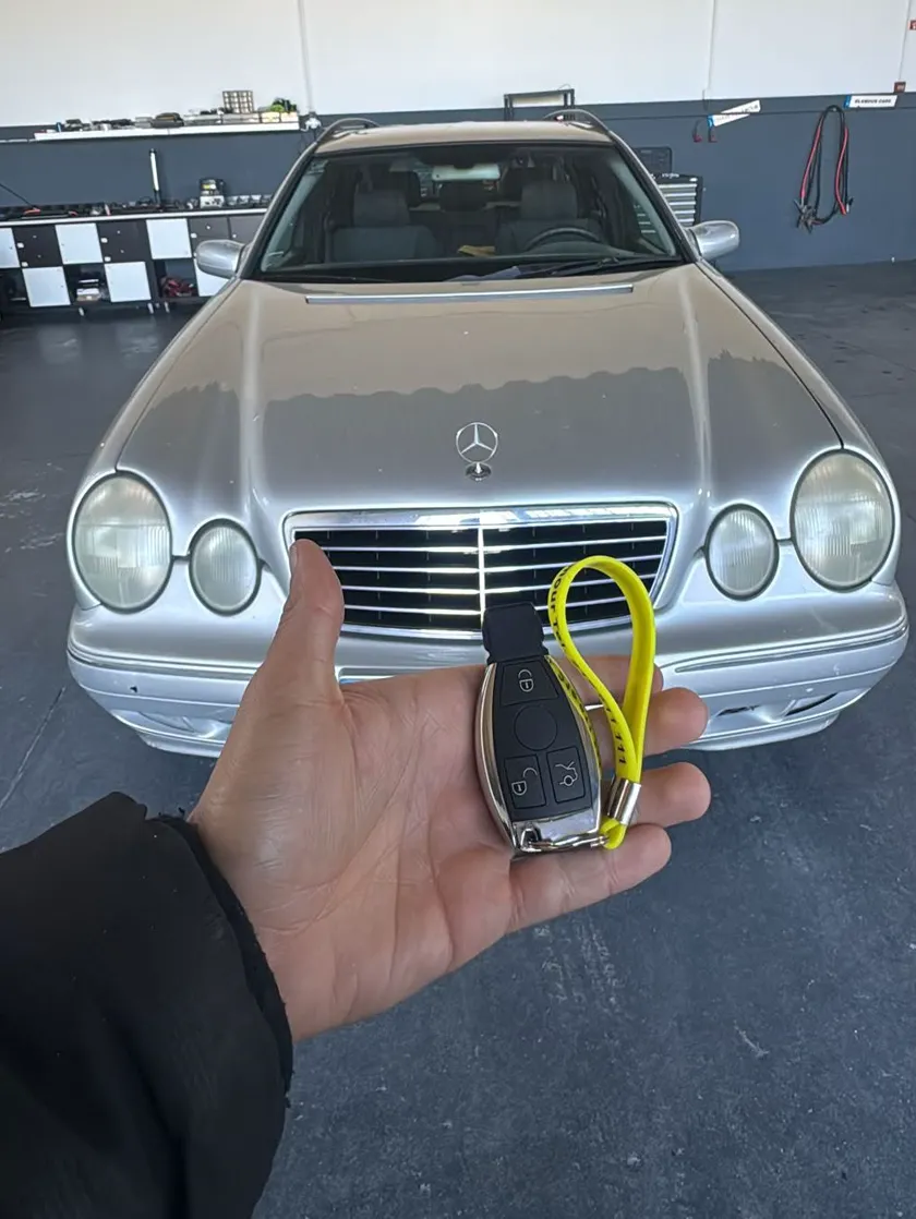 Chave de carro entregue pelo técnico, com o carro do cliente atrás